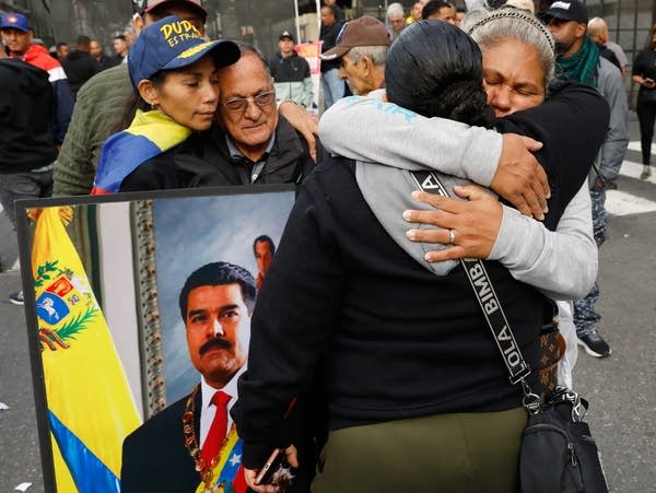 People holding signs embrace on a city street