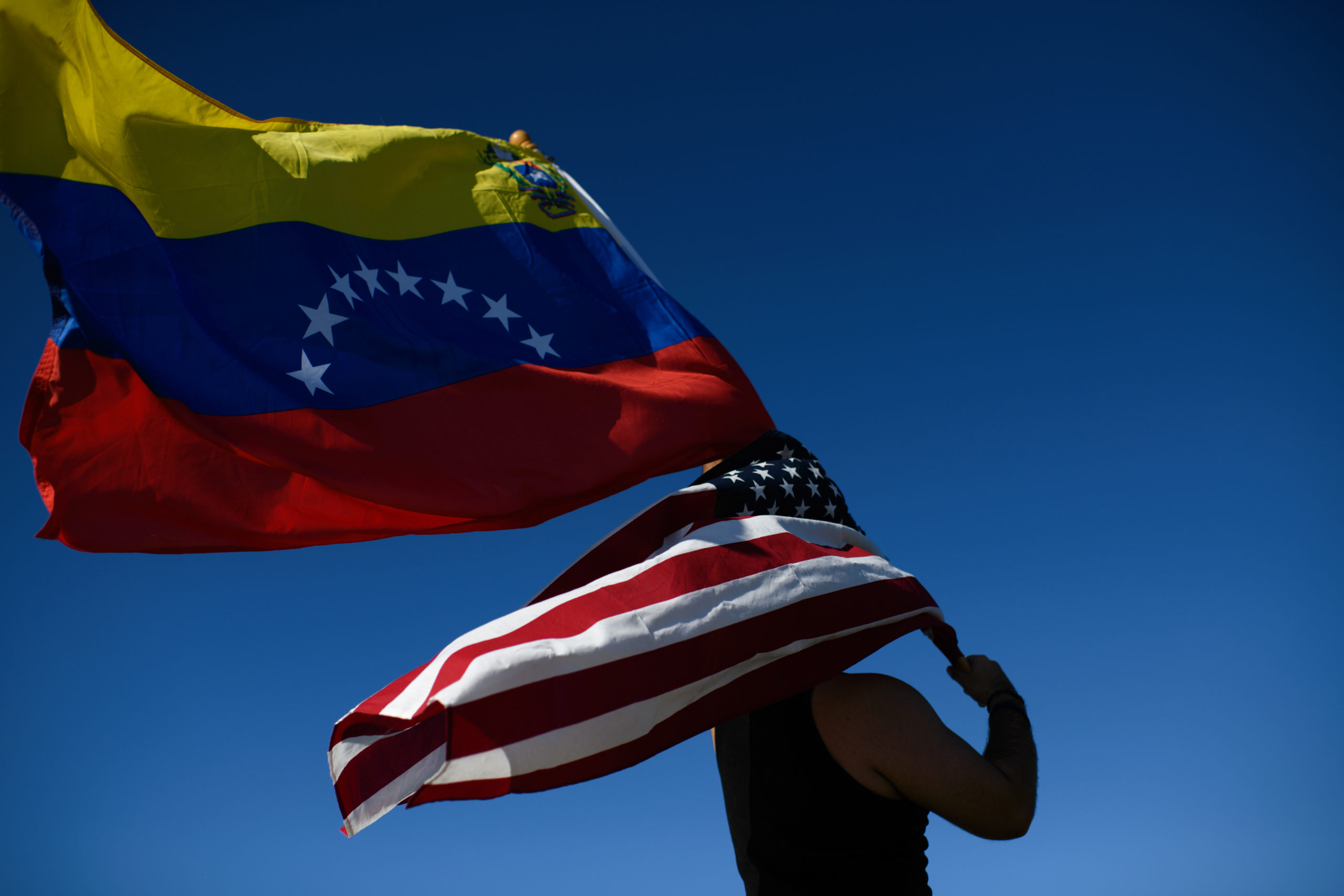 US and Venezuelan flags held by a demonstrator.