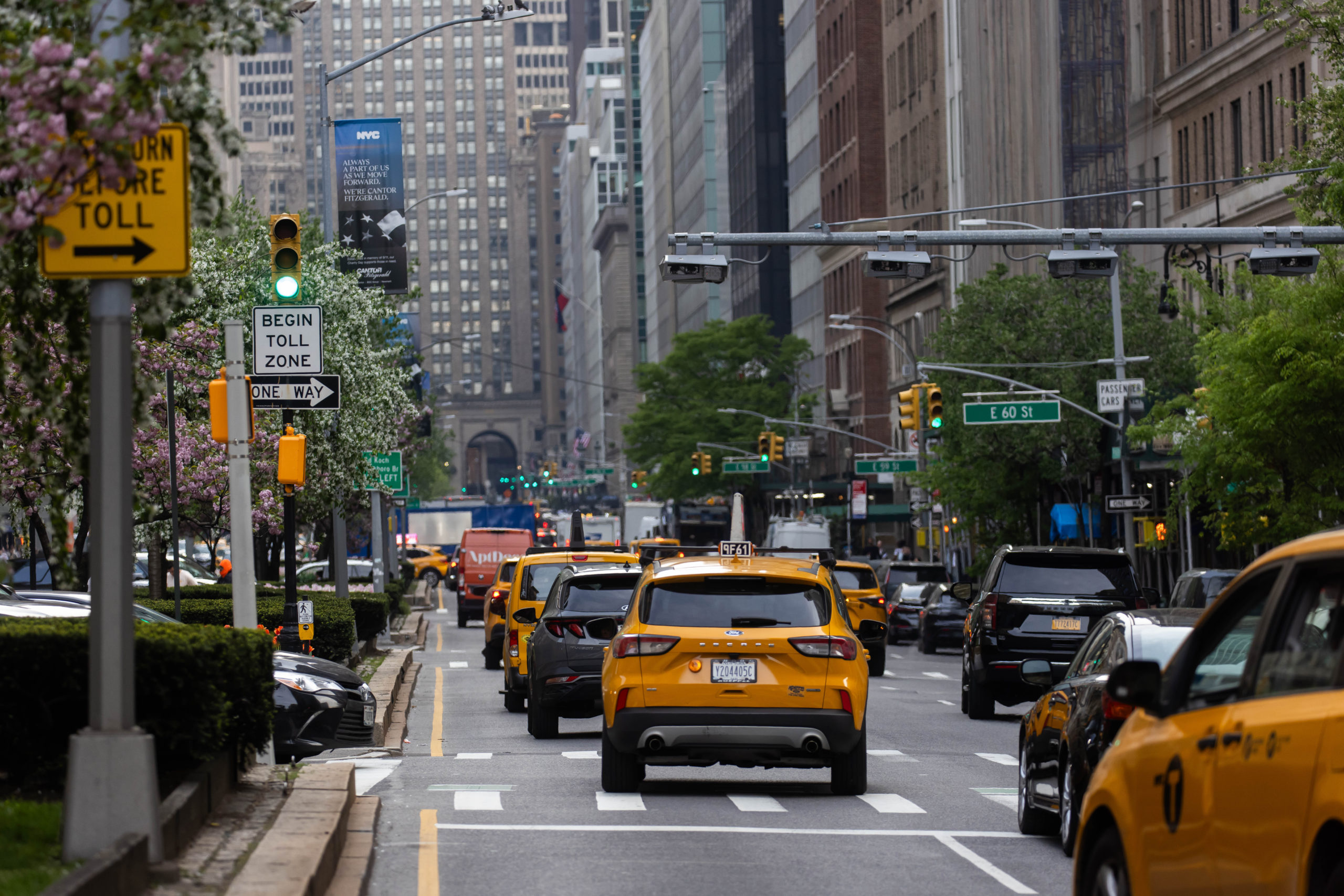 A New York city street with yellow cabs, other cars, and buildings.