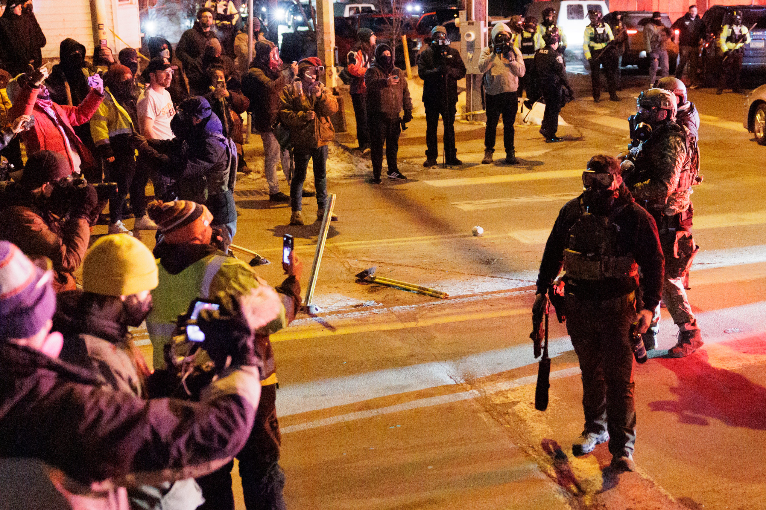 Minneapolis residents protest and film ICE agents on a nighttime street.