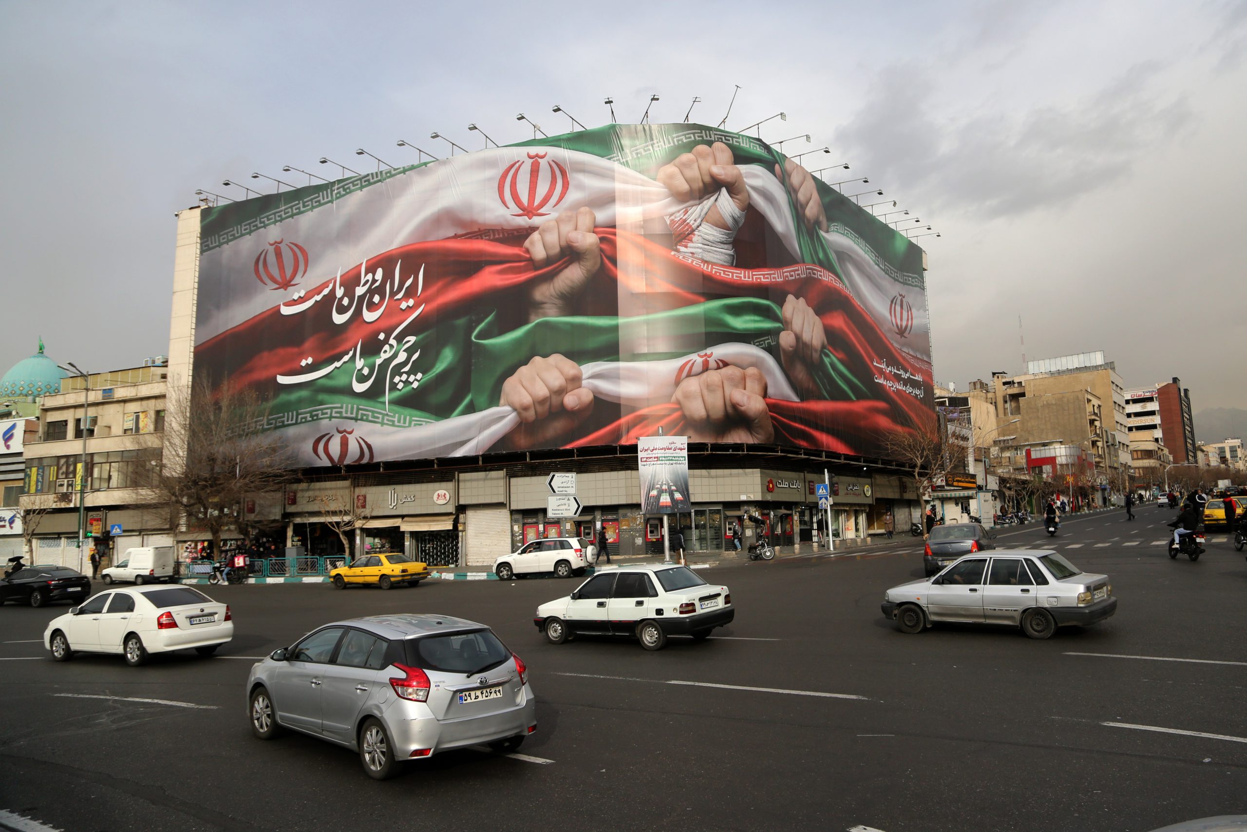Banner of fists holding Iranian flag over a busy street