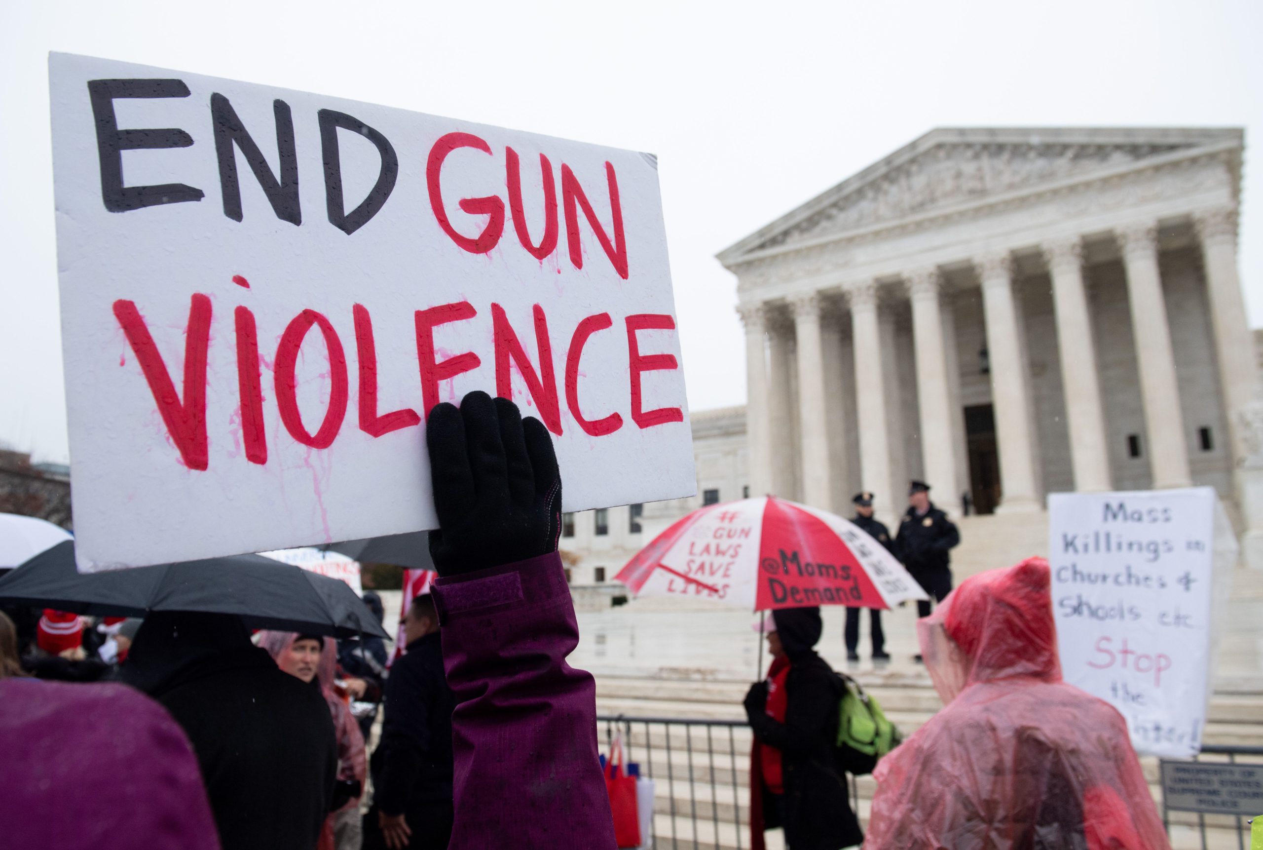 Demonstrators outside the Supreme Court holding signs to end gun violence