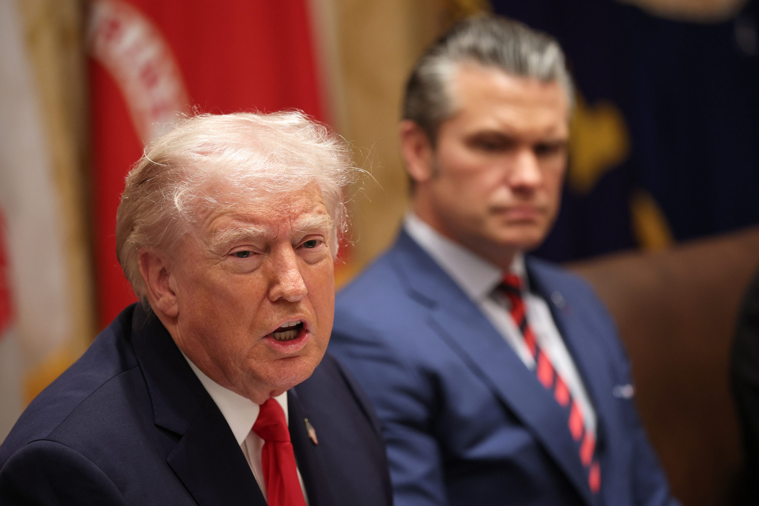 Donald Trump and Pete Hegseth seated at a table.