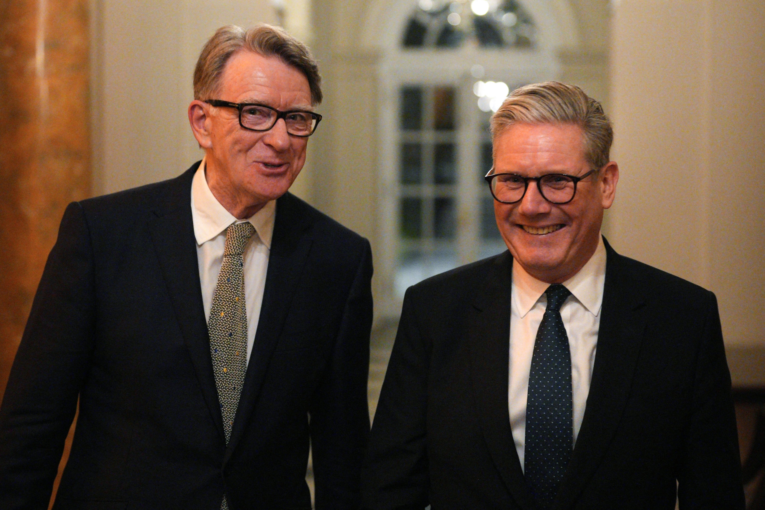 Mandelson and Starmer laughing as they walk down a hall. 