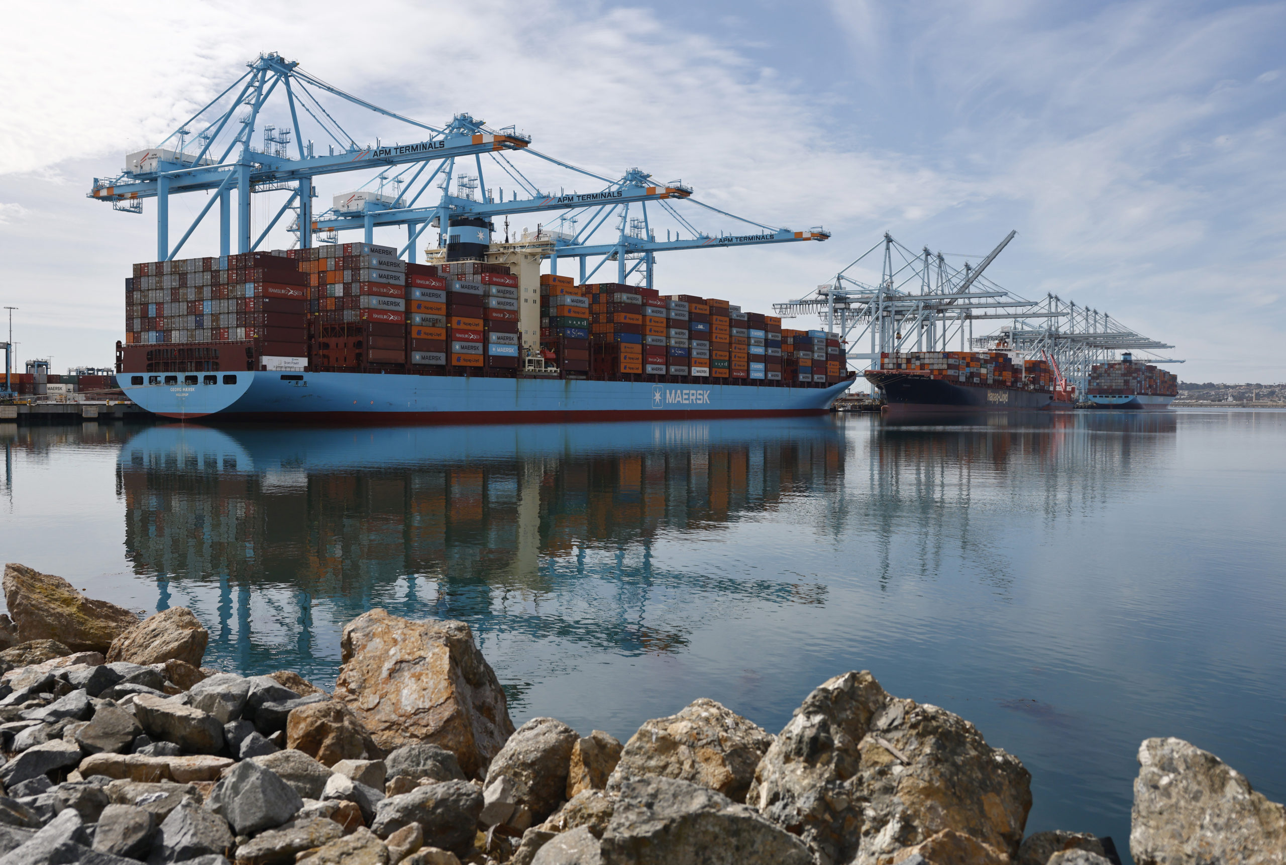 A shipping container in port with cranes overhead.