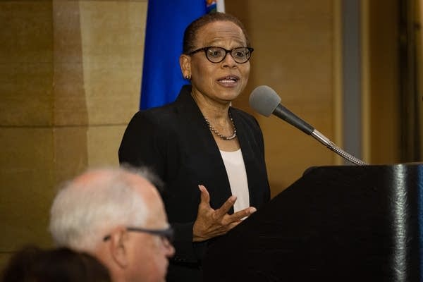 A woman speaks into a mic at a podium