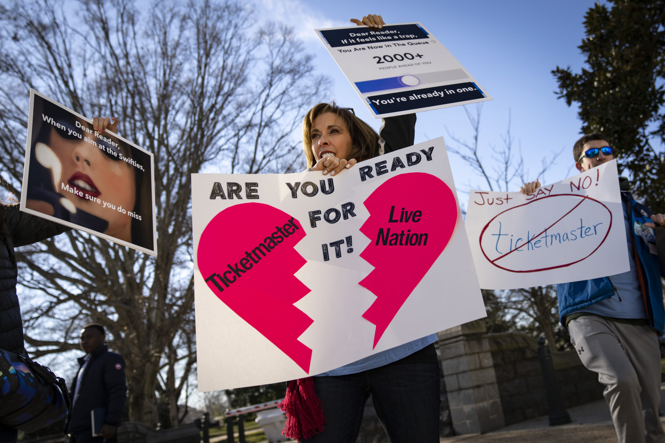 Protesters hold signs referencing Ticketmaster and Live Nation.