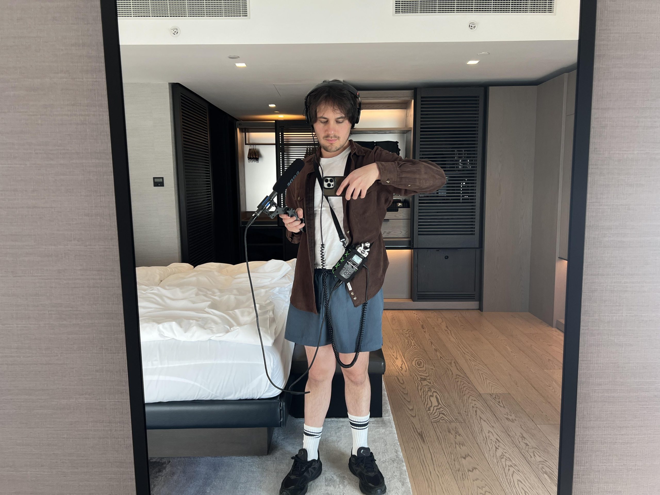 A man stands in a hotel room with his recording equipment