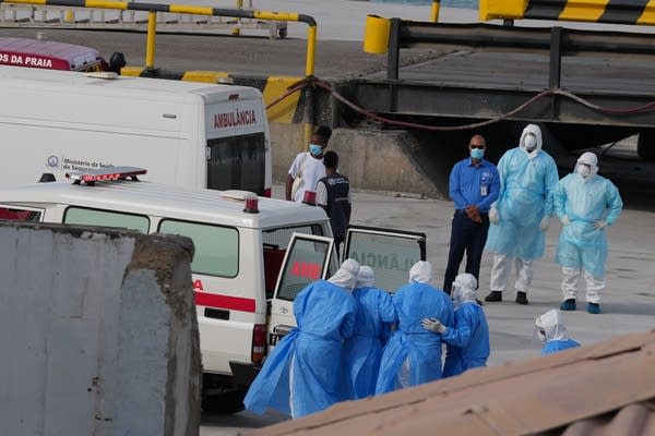 Health workers in protective gear evacuating patients