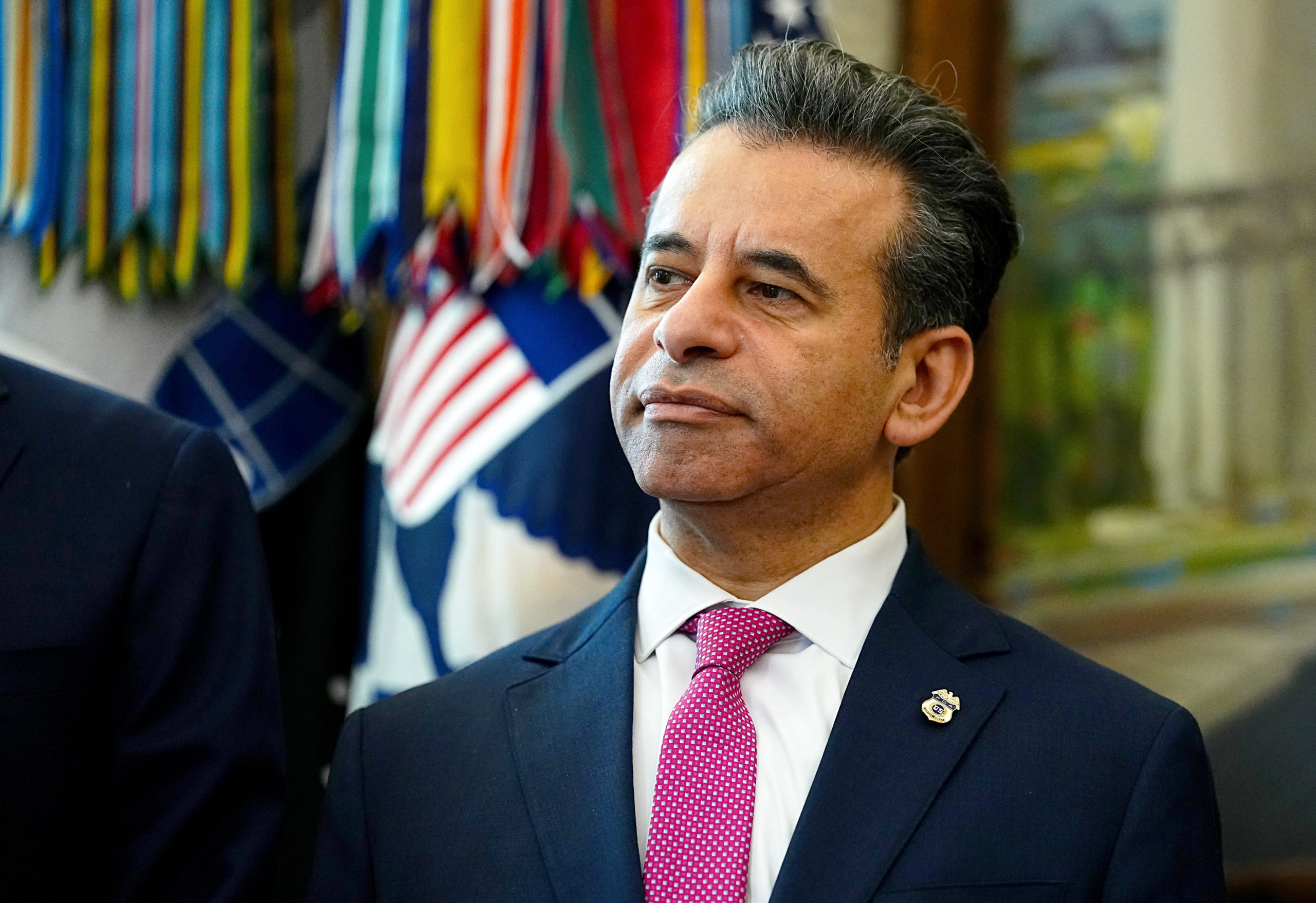 Marty Makary, a clean-shaven man wearing a navy suit with a fuchsia tie, stands in the Oval Office.