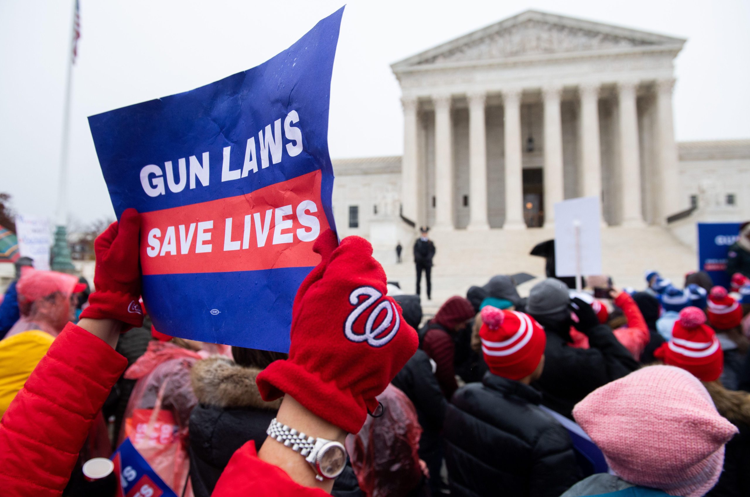 Protesters outside the Supreme Court holding a sign that reads gun laws save lives