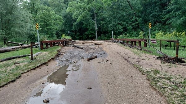 Gravel, logs and other debris cover a bridge after a flash flood