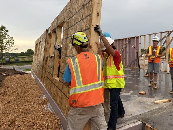 Two people in vests putting up a wall