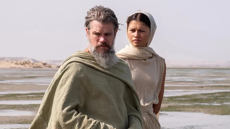 A gray-bearded white man stands in front of a young Black woman. Both are wearing robes. Behind them a series of tidal pools dissolve into the sea.