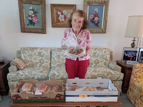Woman stands in living room with boxes of covered baked goods