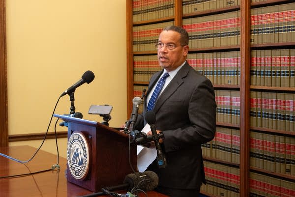 A man stands behind a podium to speak to press.