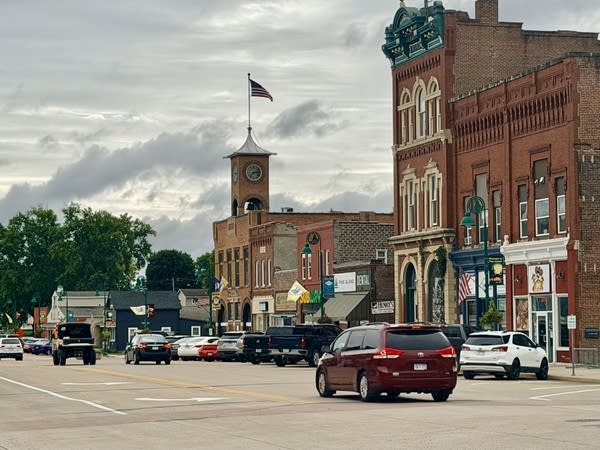 Cars drive through downtown of a small main street.