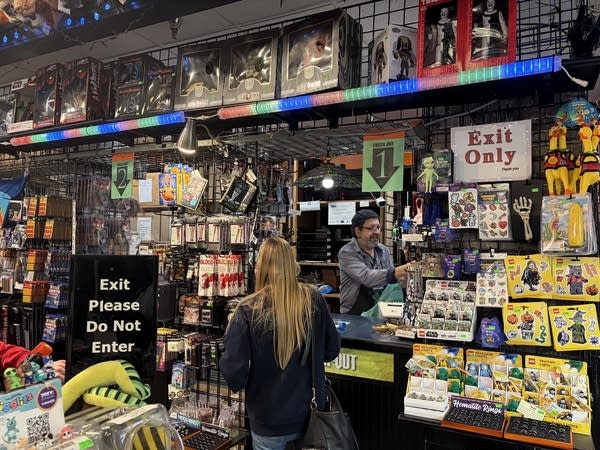 Wide shot of a costume shop worker ringing up a woman at a counter.