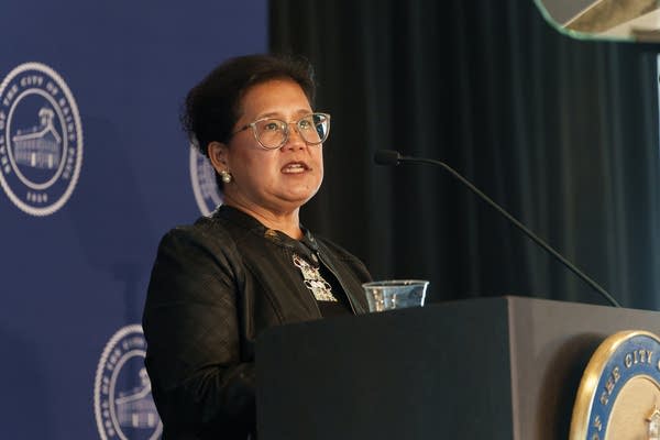 A woman speaks at a podium into a microphone.