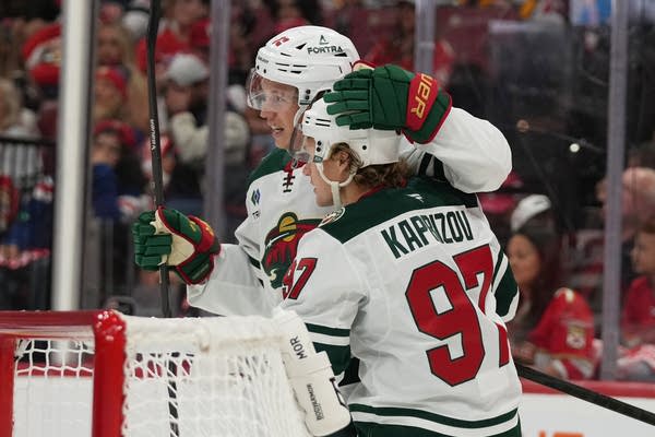 Two hockey players embrace in celebration after a goal.