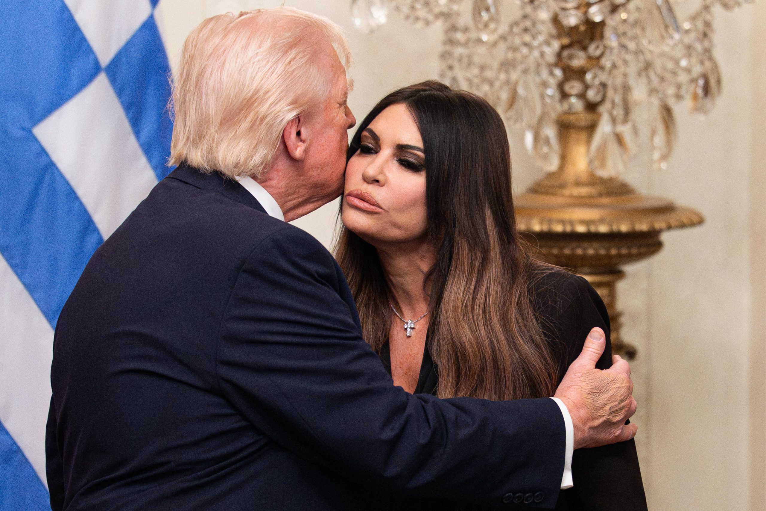 Trump turns away from the camera and embraces Kimberly Guilfoyle with a hand on her shoulder.