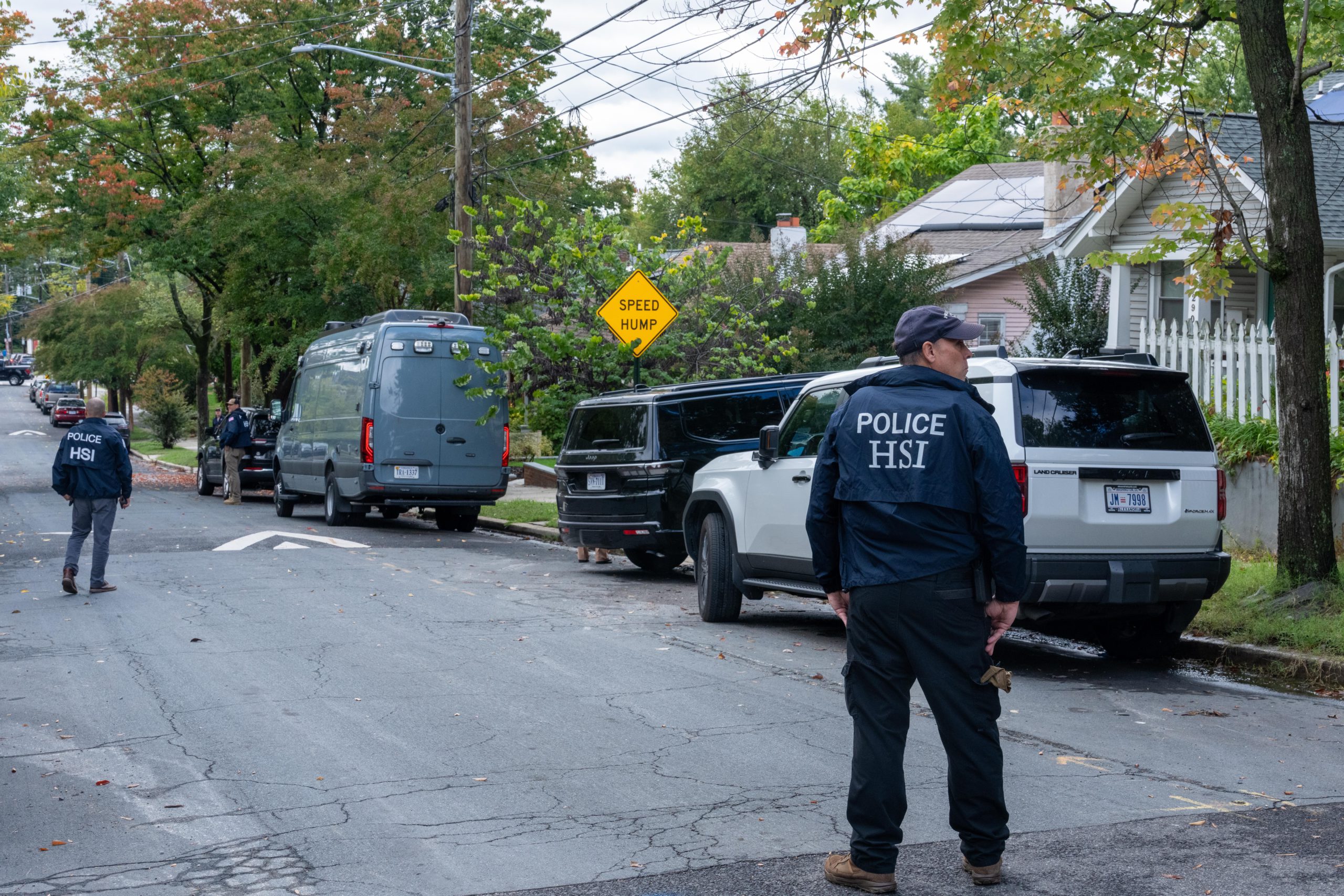 Men wearing homeland security jacket standing in the middle of a neighborhood street