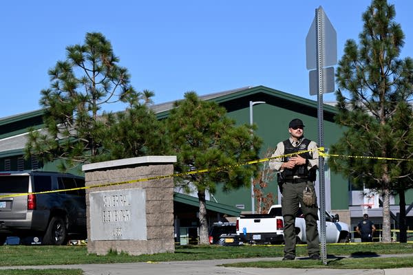 A police officer stands next to a taped-off scene at an elementary school.
