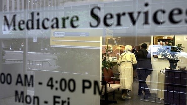 Two people walk inside a Medicare Services office.