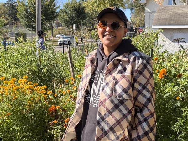 A person stands in a garden with marigolds. 