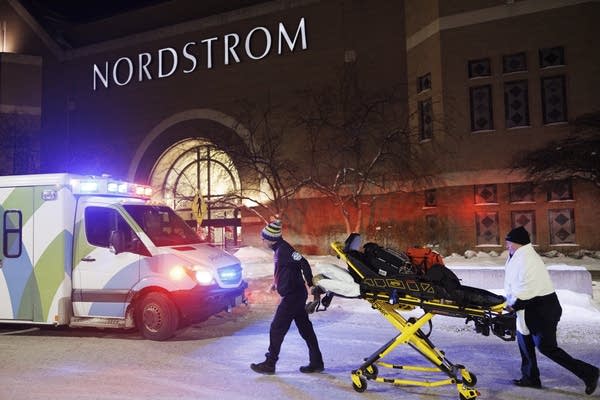 two people transporting emergency equipment next to an abulance