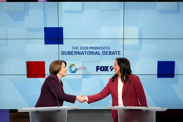 two candidates for governor shake hands across two podiums