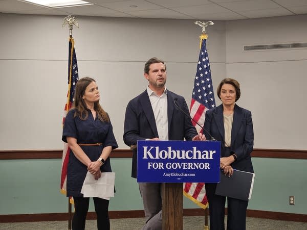 Three people stand by a podium