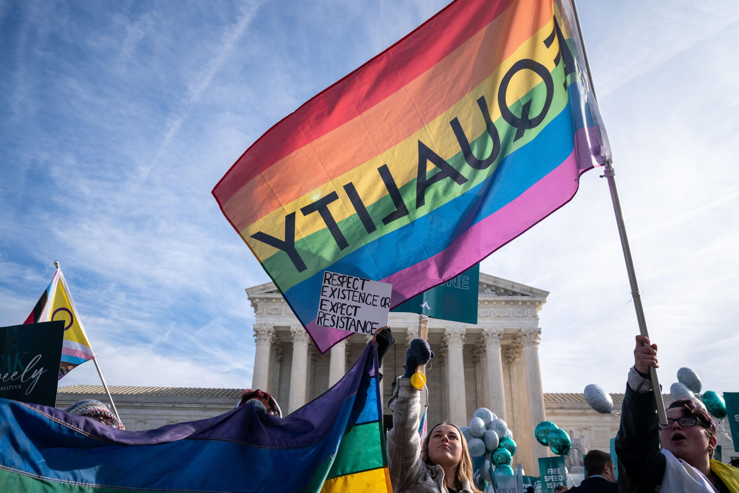 People outside the Supreme Court building holding equality signs